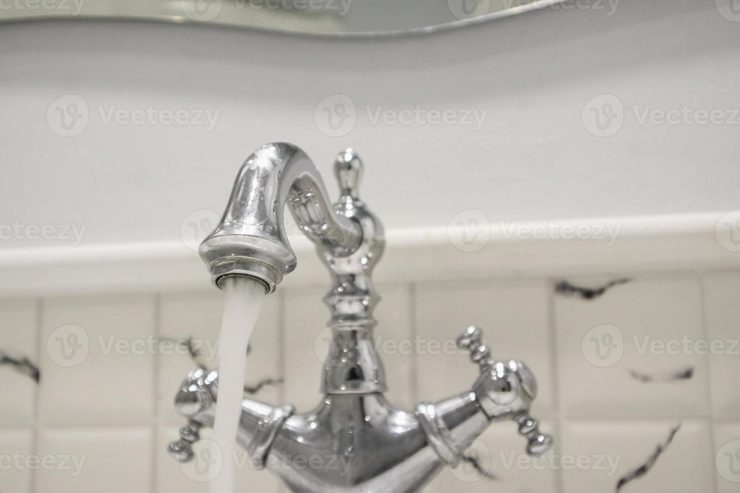 Water from vintage style faucet in the bathroom photo