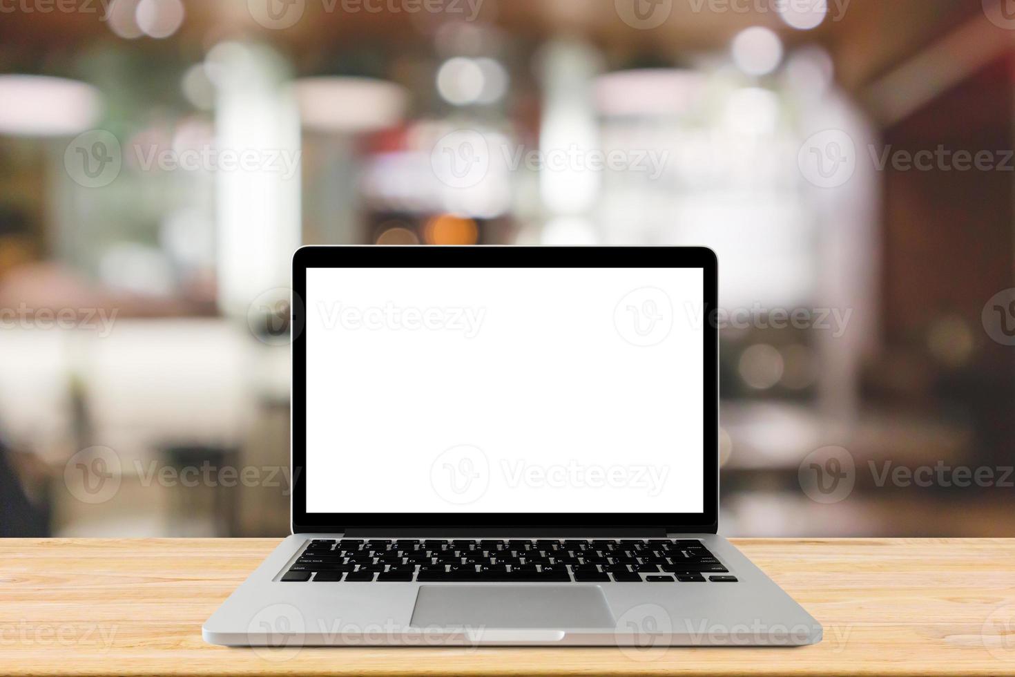 Blank screen laptop computer on wood table top with blur cafe restaurant with abstract bokeh light defocused background photo