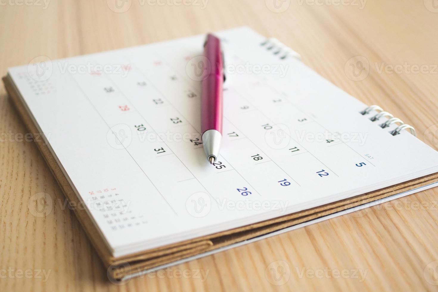 página de calendario con bolígrafo sobre fondo de mesa de madera foto