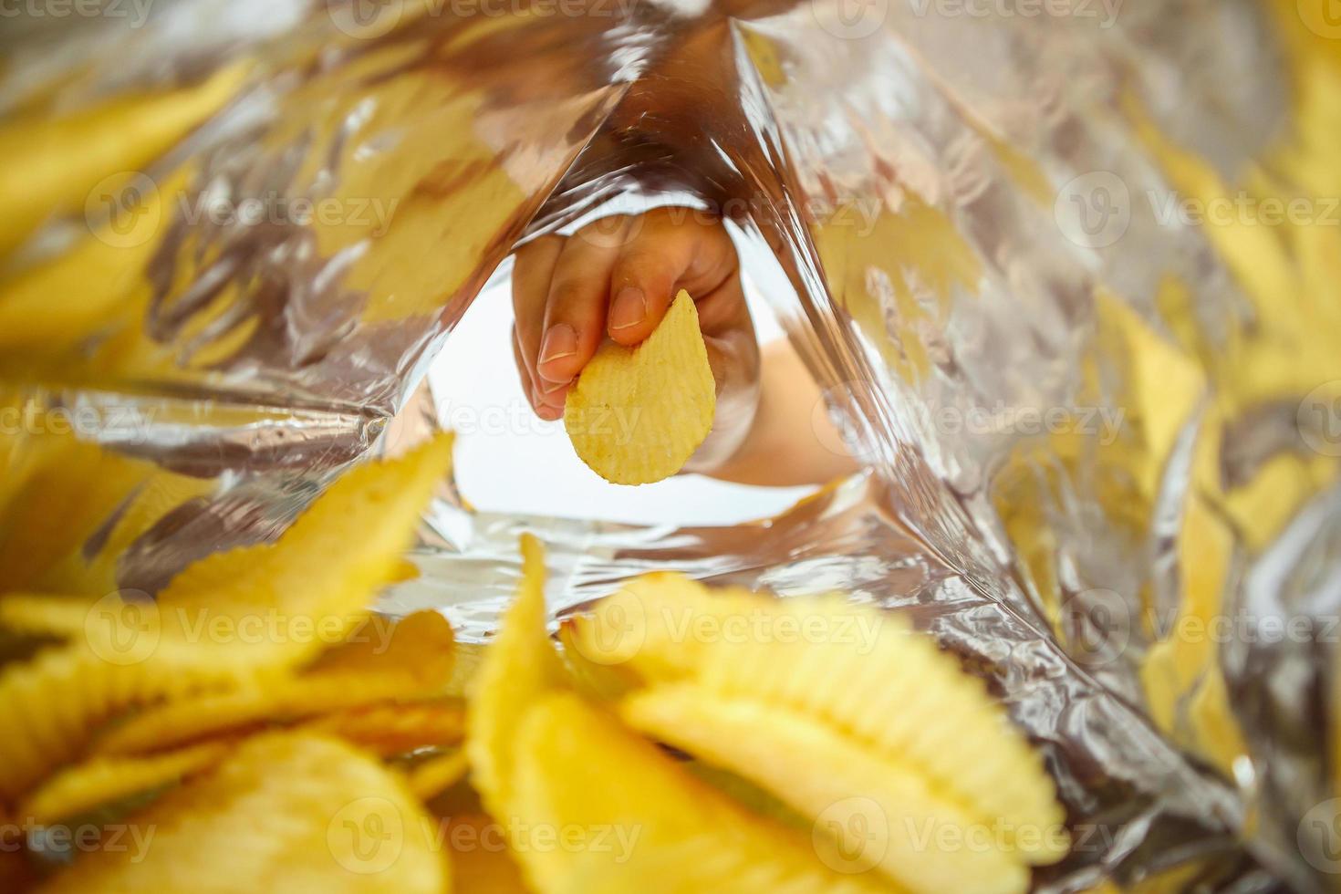 Sostenga a mano papas fritas dentro de una bolsa de aluminio para refrigerios foto