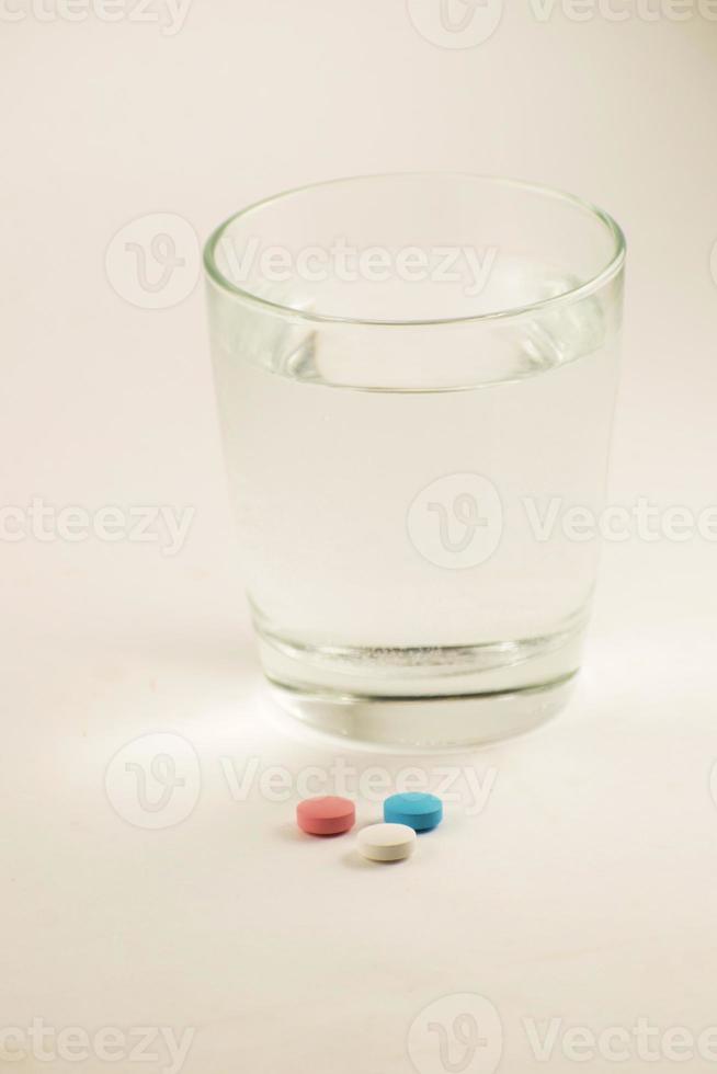 Glass of water and pills on white background. A glass of water and vitamins. Healthy lifestyle, nutritional supplements. photo