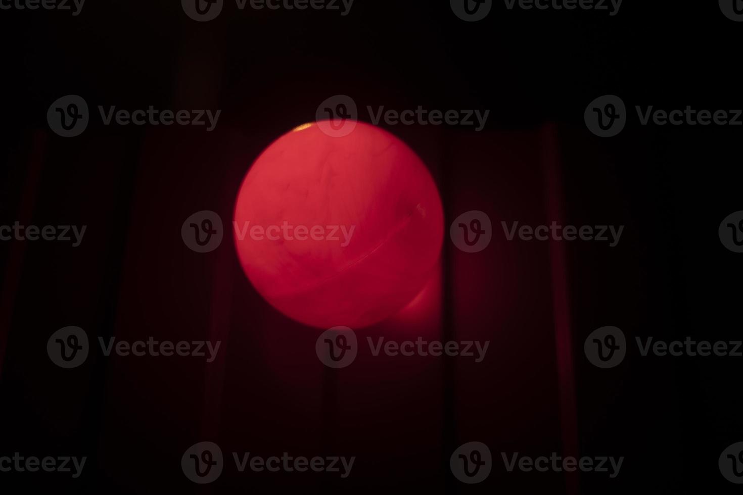 Red ball in dark. Signal lamp on fence. photo