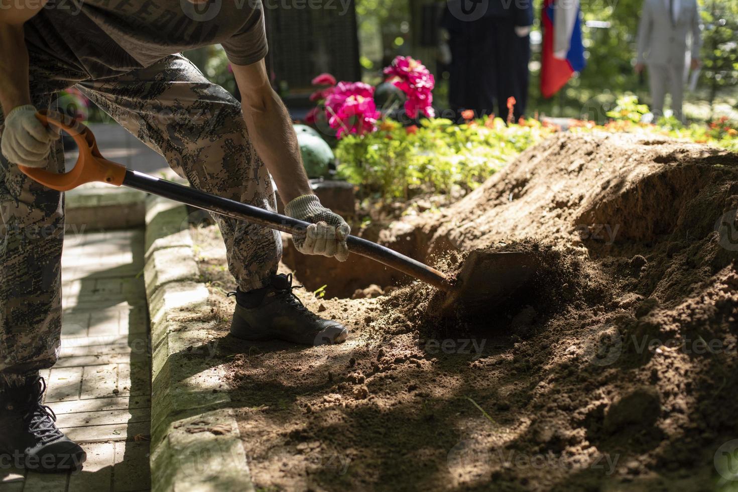 Man digs grave. Guy with shovel digs ground. Funeral details. photo