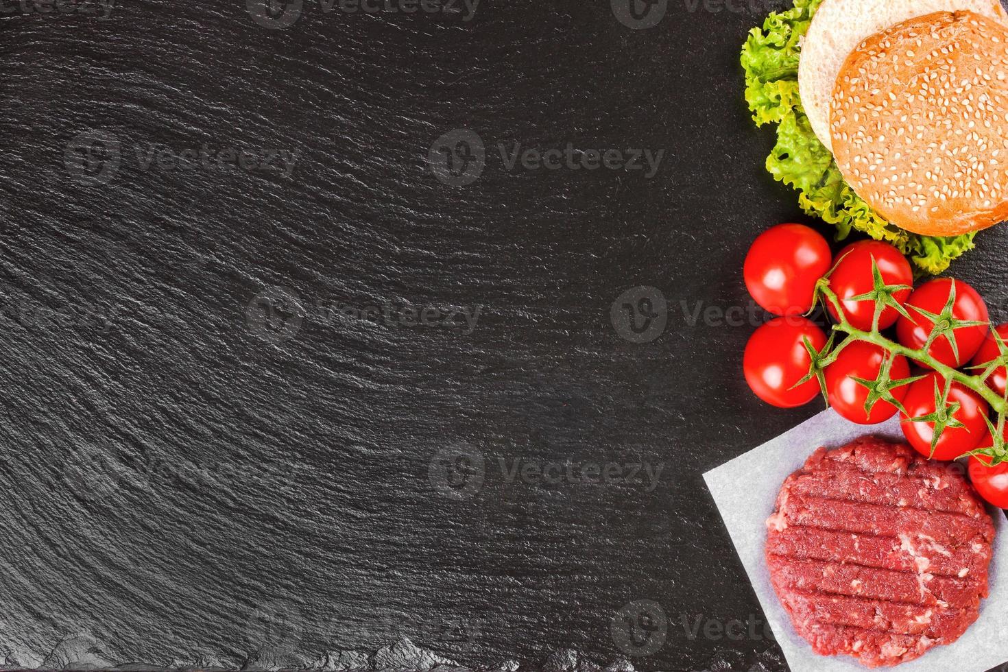 The raw ingredients for the homemade burger on black slate background. Top view. photo