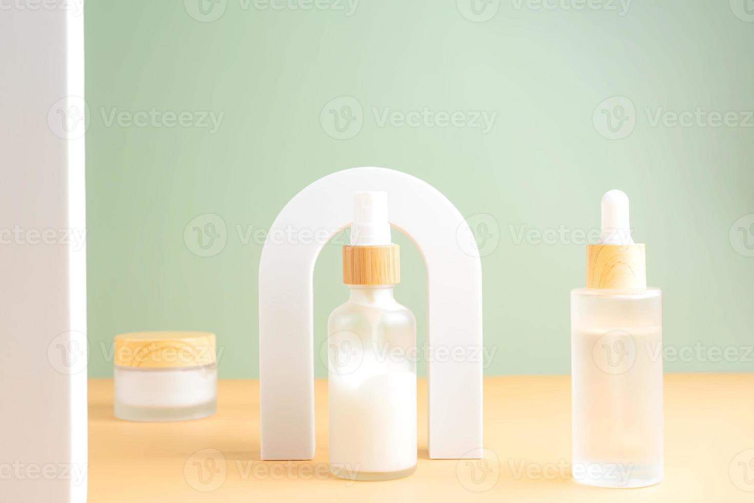 Beauty product concept. Jar of cream and bottles of serum on beige background in the arch. Front view. Trendy showcase with natural colors photo