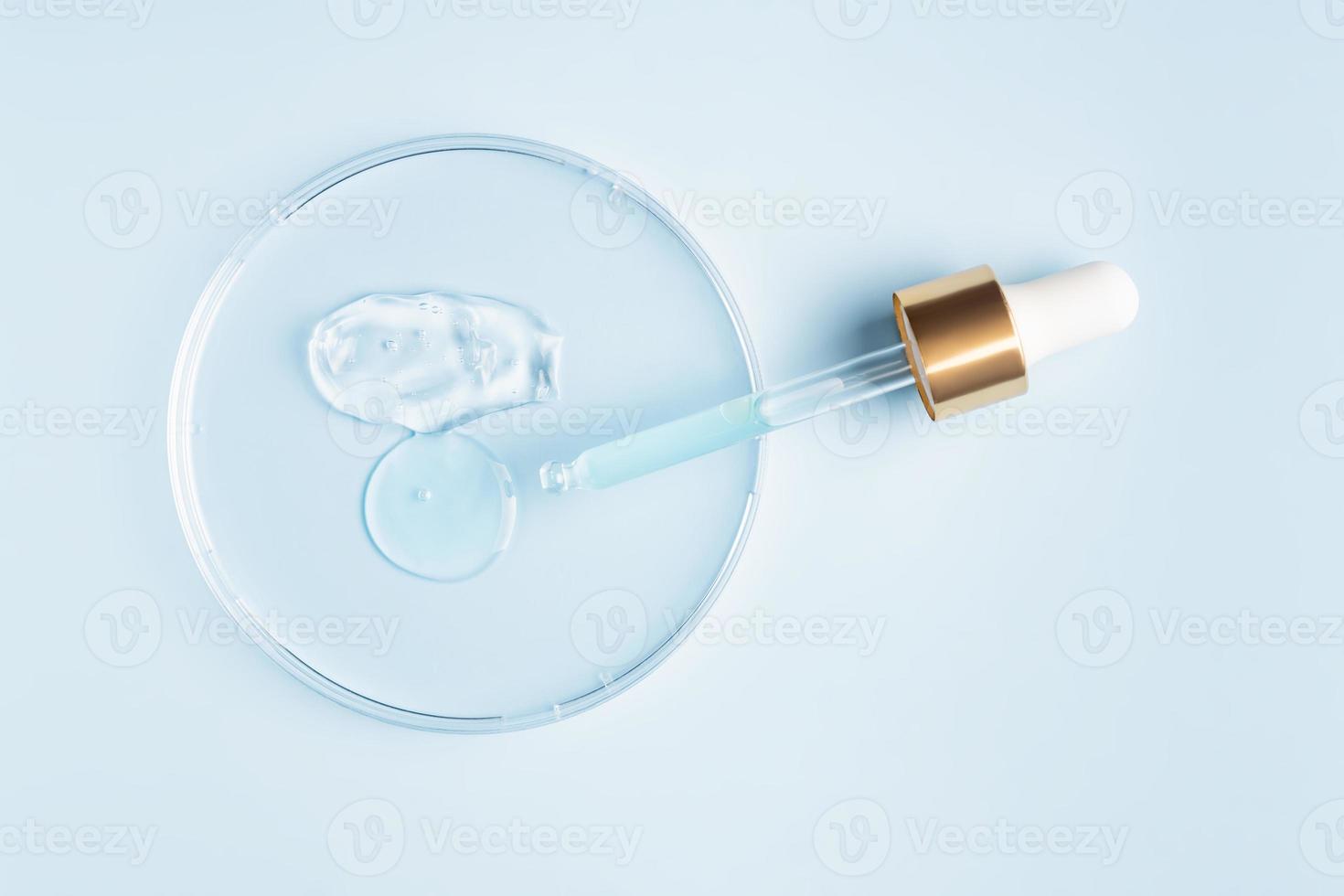 smear of cosmetic gel stroke and round transparent drop of serum in a petri dish on a blue background. Concept laboratory tests and research, making and testing cosmetic photo