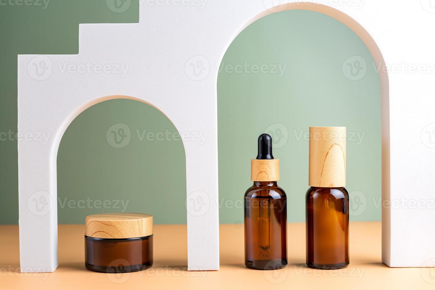 conjunto de cosméticos para el cuidado facial. suero facial de colágeno de belleza en un frasco cuentagotas de vidrio y crema facial en arco sobre fondo beige y verde. sesión de moda de envases cosméticos. foto