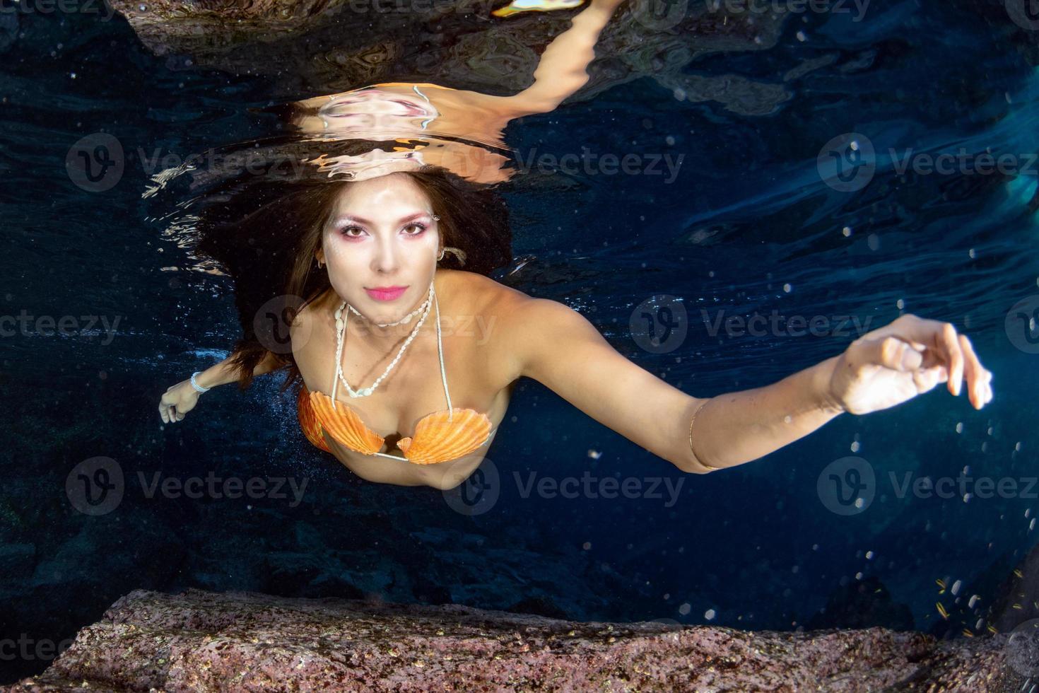 sirena nadando bajo el agua en el mar azul profundo foto