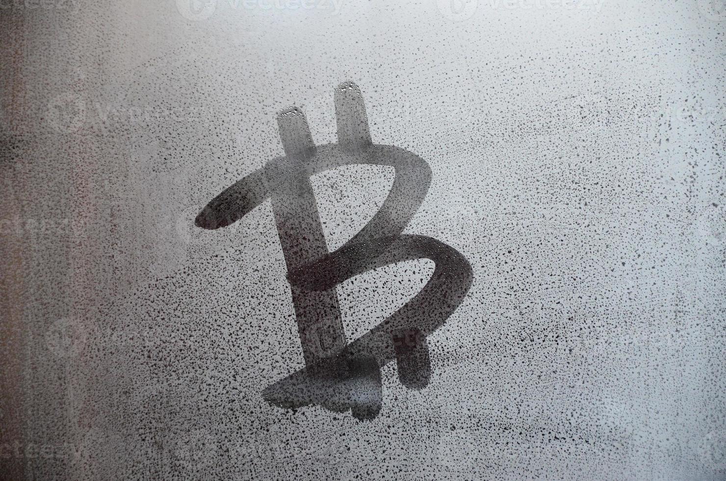 The bitcoin symbol on the misted sweaty glass. Abstract background image. Cryptocurrency concept photo