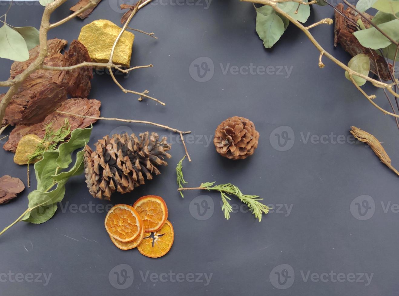 Christmas flat lay background made of natural winter things on dark blackboard. Fir tree branch, natural forest acorn, plants, dry slices of oranges. photo