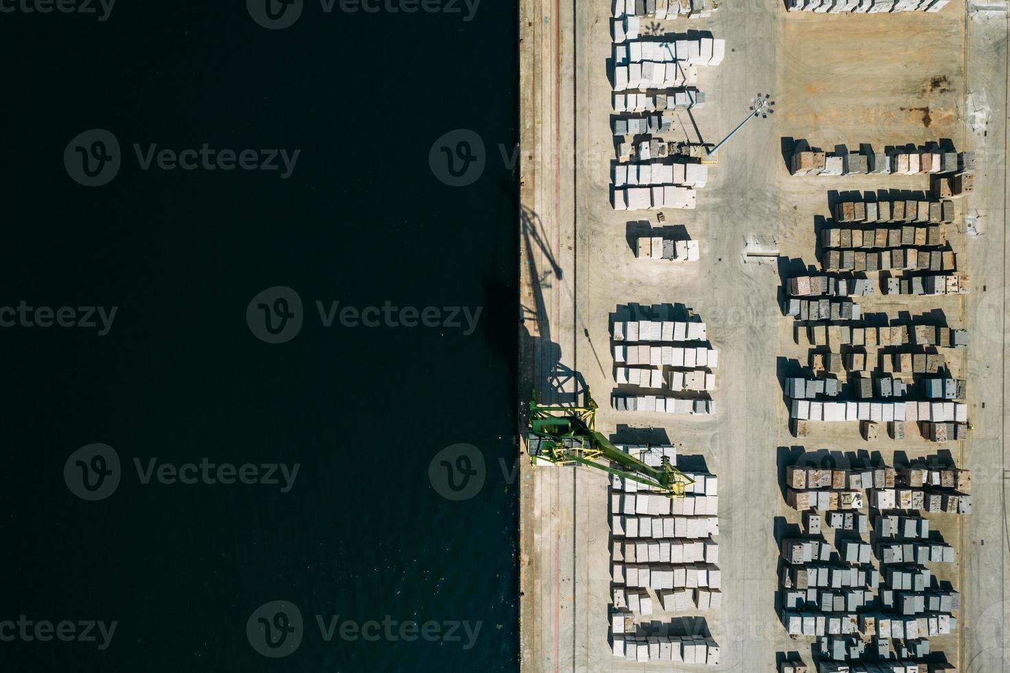 Aerial drone top down view of containers and concrete blocks spread across a busy port, logistic and international trade concept photo