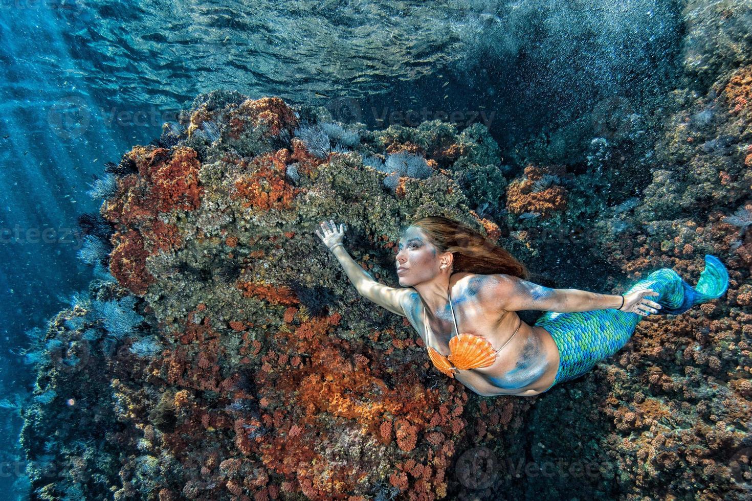 hermosa sirena nadando bajo el agua en el mar azul profundo foto