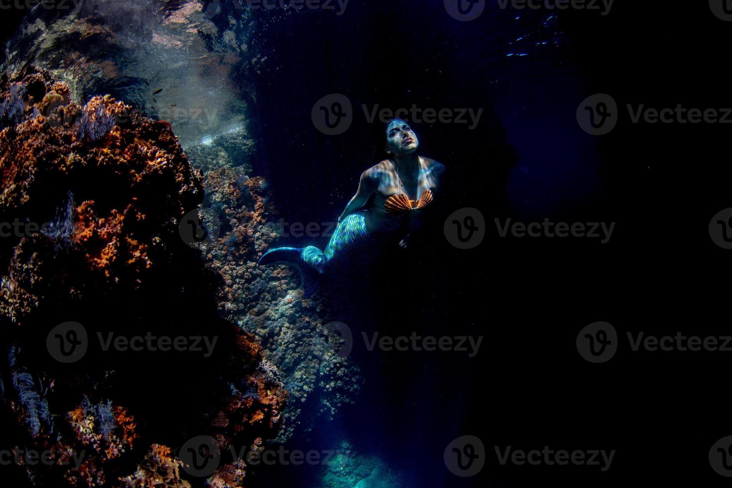 Mermaid swimming underwater in the deep blue sea photo