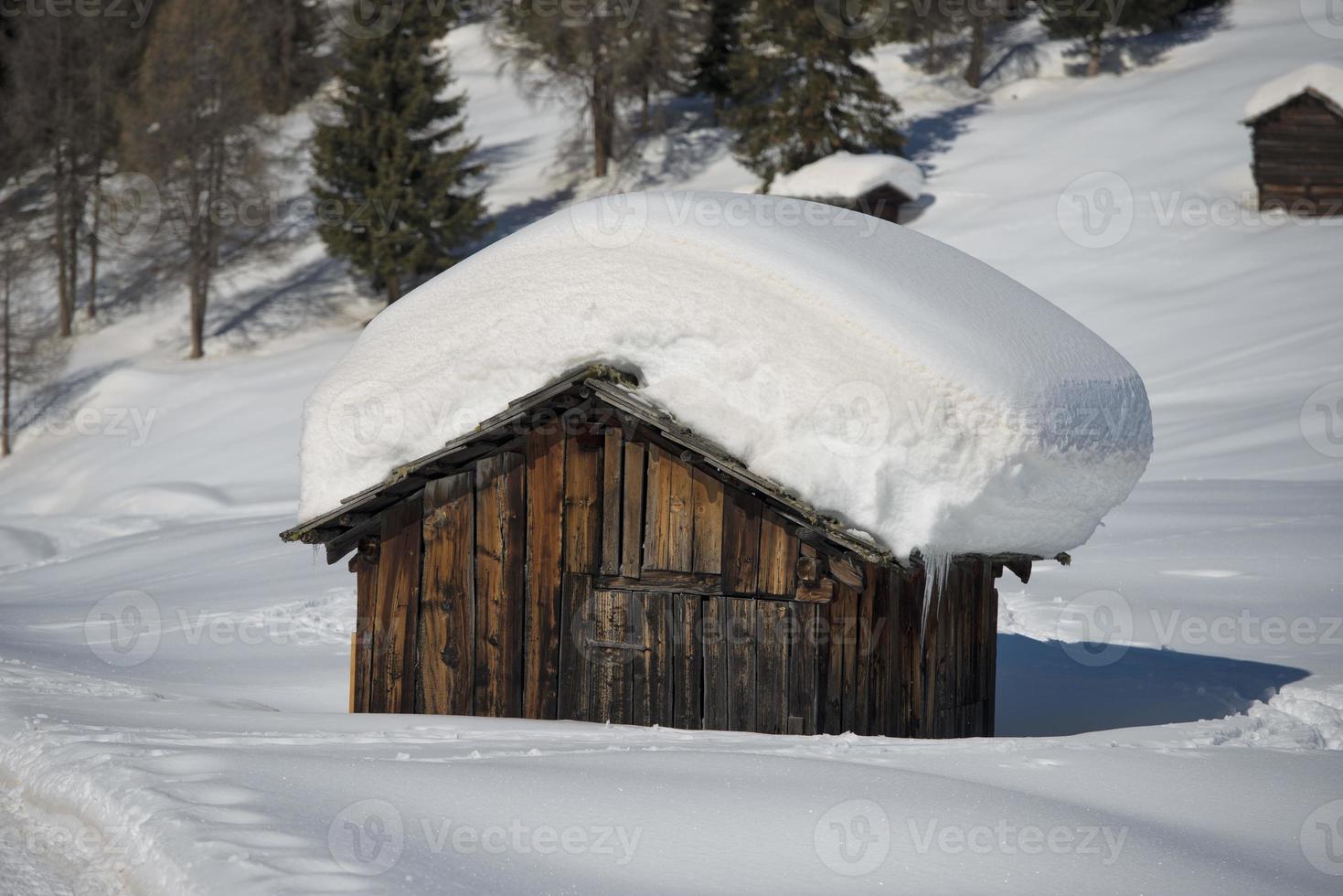 una cabaña de madera en el fondo de la nieve invernal foto