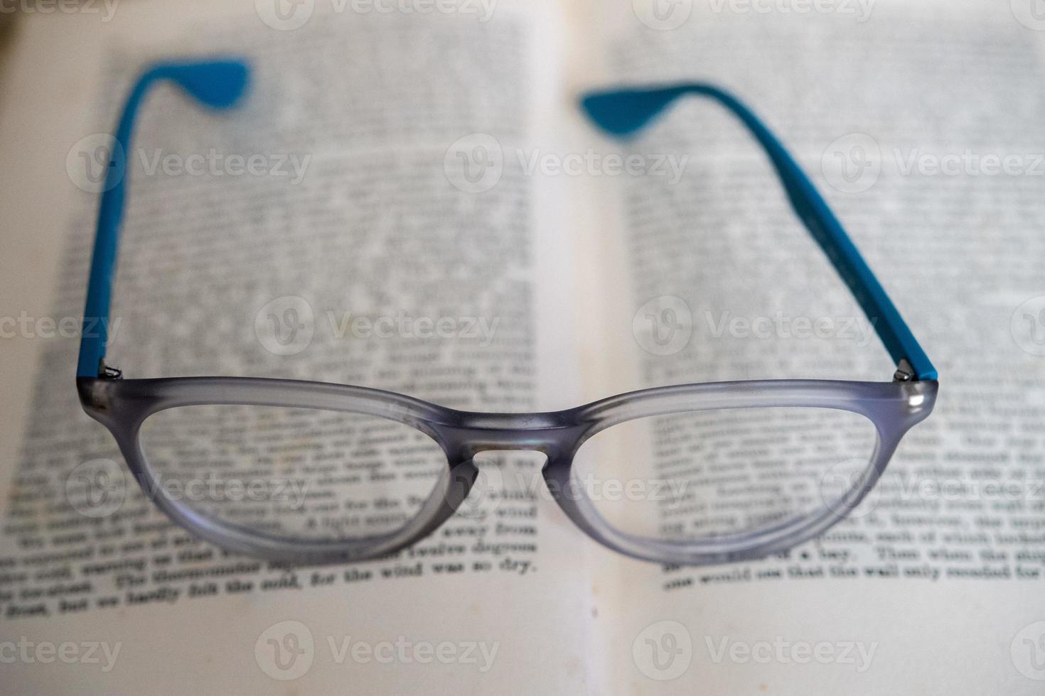 light blue reading glasses isolated on a book photo