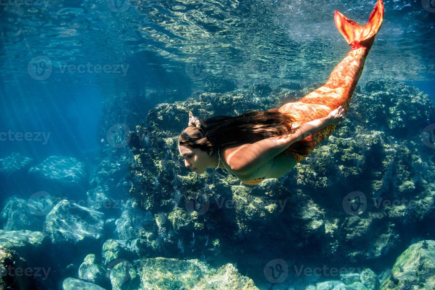 sirena nadando bajo el agua en el mar azul profundo foto