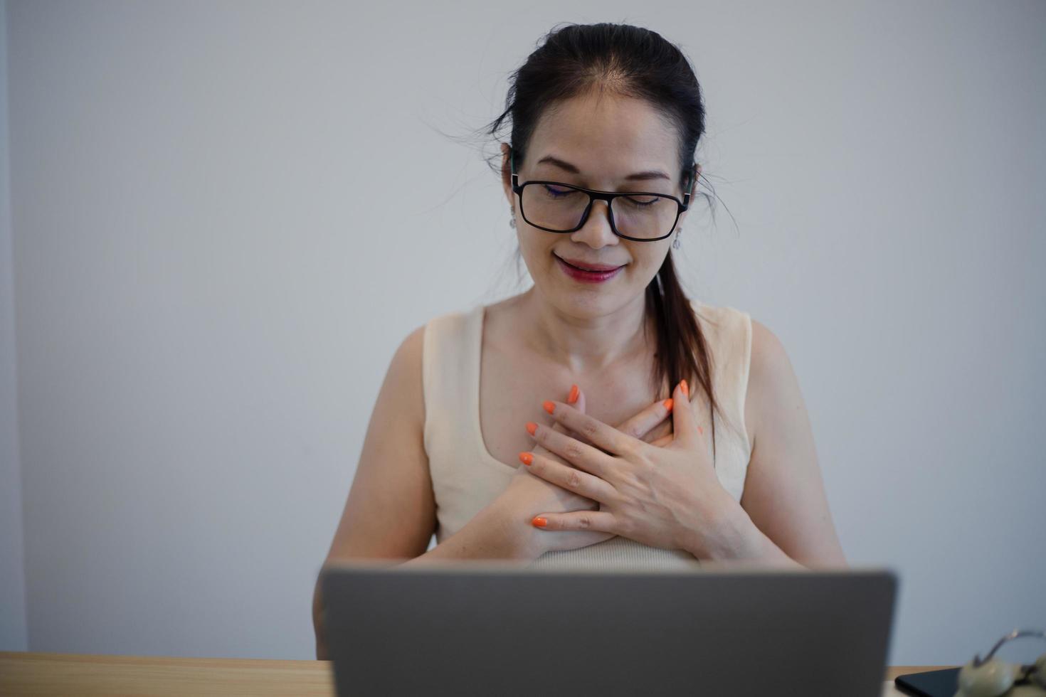 Asian woman working and smiling with heart on chest, health concept. photo