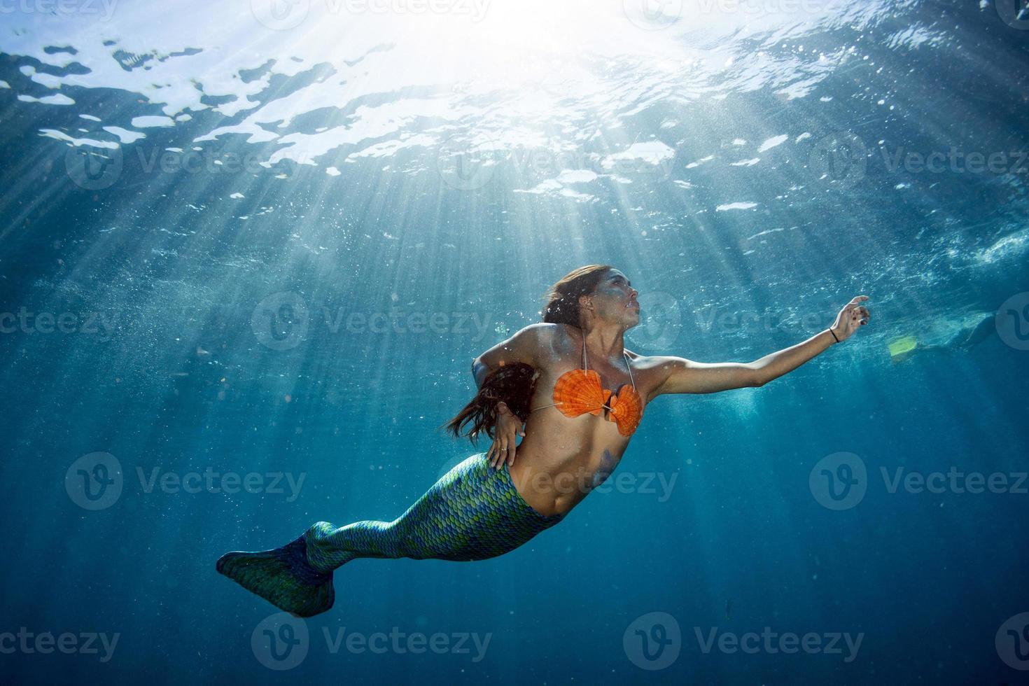 sirena nadando bajo el agua en el mar azul profundo foto