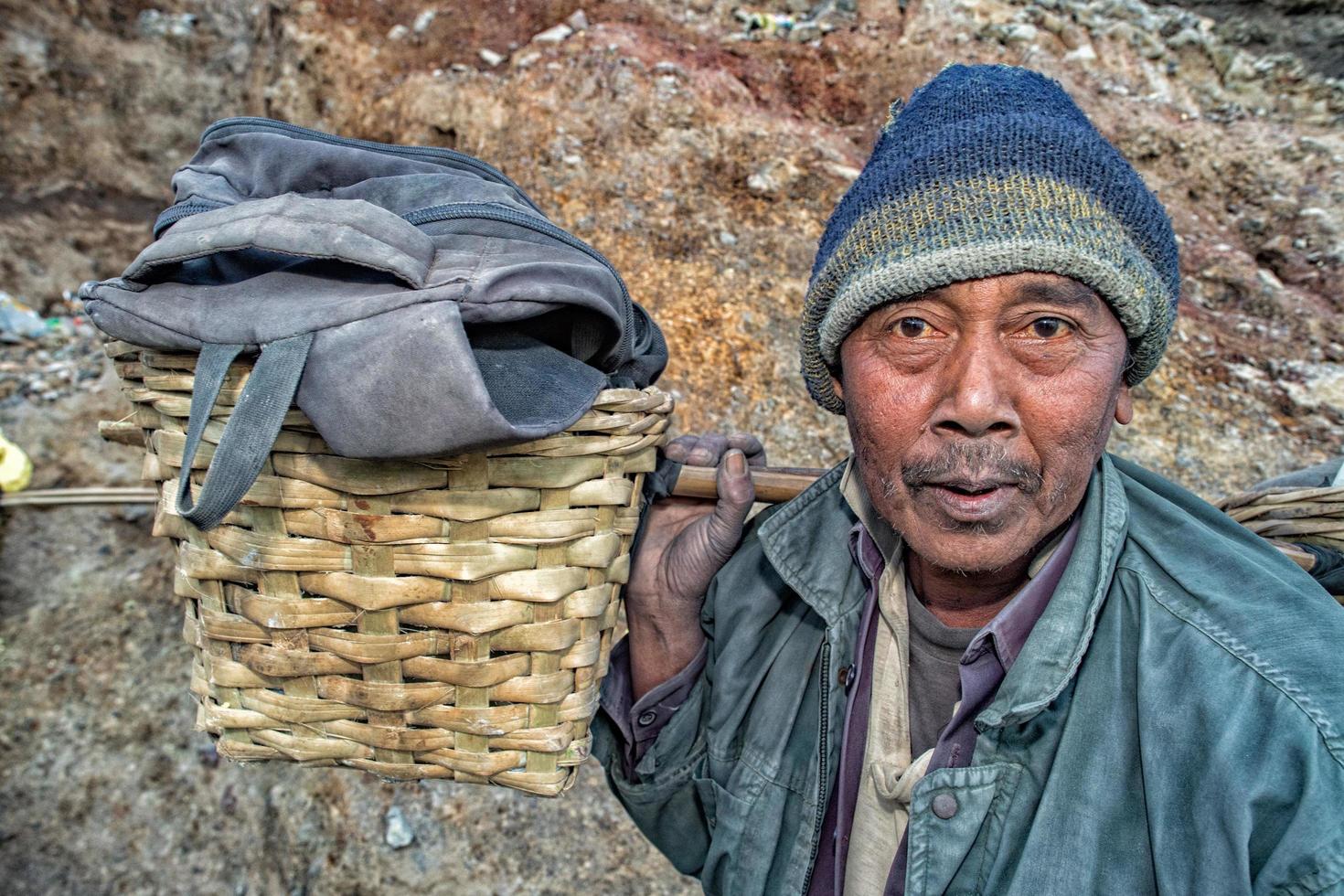 Java, Indonesia - 9 de agosto de 2016 - mineros que transportan azufre de las llamas azules del volcán ijen en la noche foto