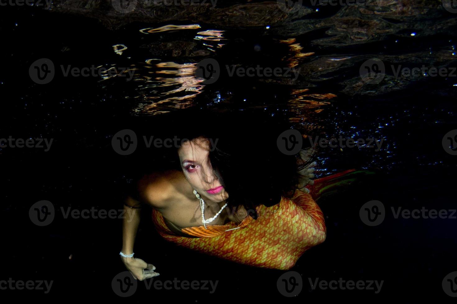 sirena nadando bajo el agua en el mar azul profundo foto