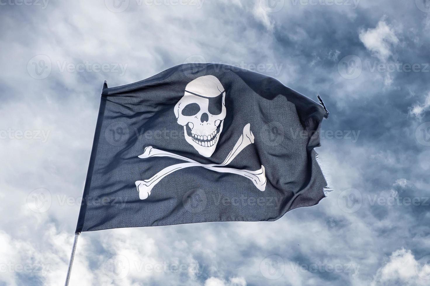 waving pirate flag jolly roger on sky background photo