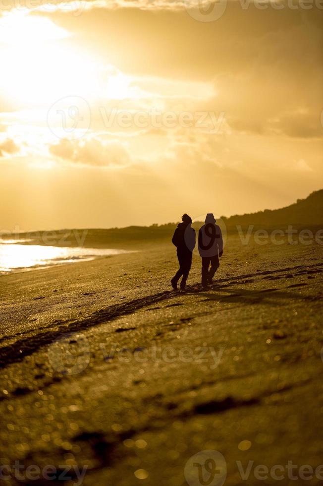 man and woman silhouette on beach at sunrise photo