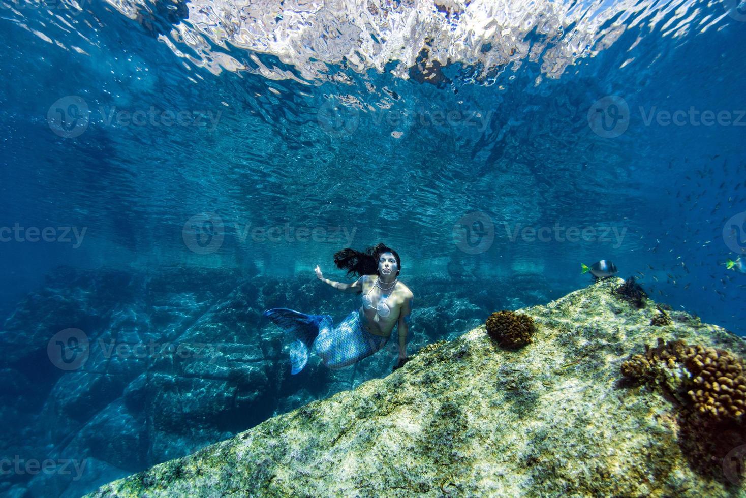 Mermaid swimming underwater in the deep blue sea photo