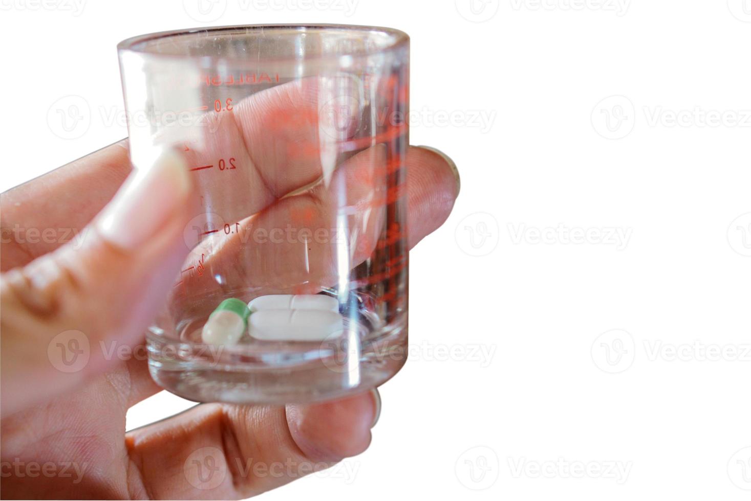 Cápsula y tableta recogidas a mano en un aislado de vidrio médico sobre fondo blanco. foto