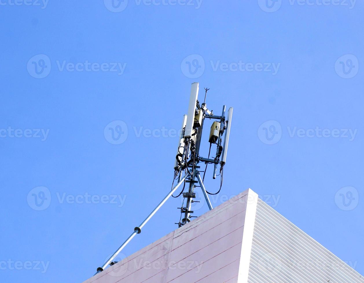 Communication tower with antennas on the top of building and bright blue sky background. photo