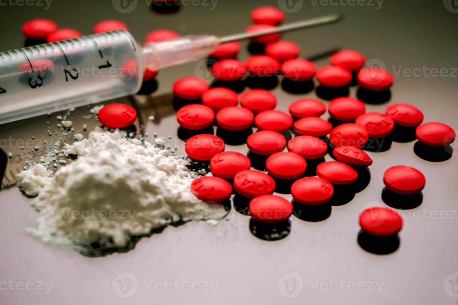 jeringa de plástico colocada en una aguja médica y polvo blanco con aislado de medicina de píldora roja sobre fondo negro. supongamos que la heroína y la anfetamina o la adicción a los estupefacientes. foto