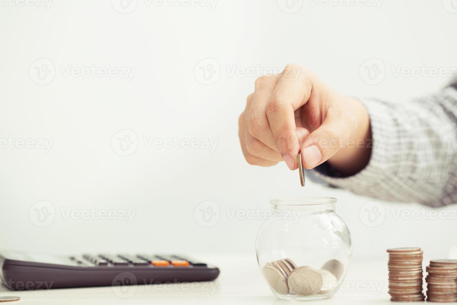 close up hand business man accounting calculate calculator expenses with savings money coins stacked row with hand putting coins Coins drop into piggy bank. concept Write Finance accounting. photo