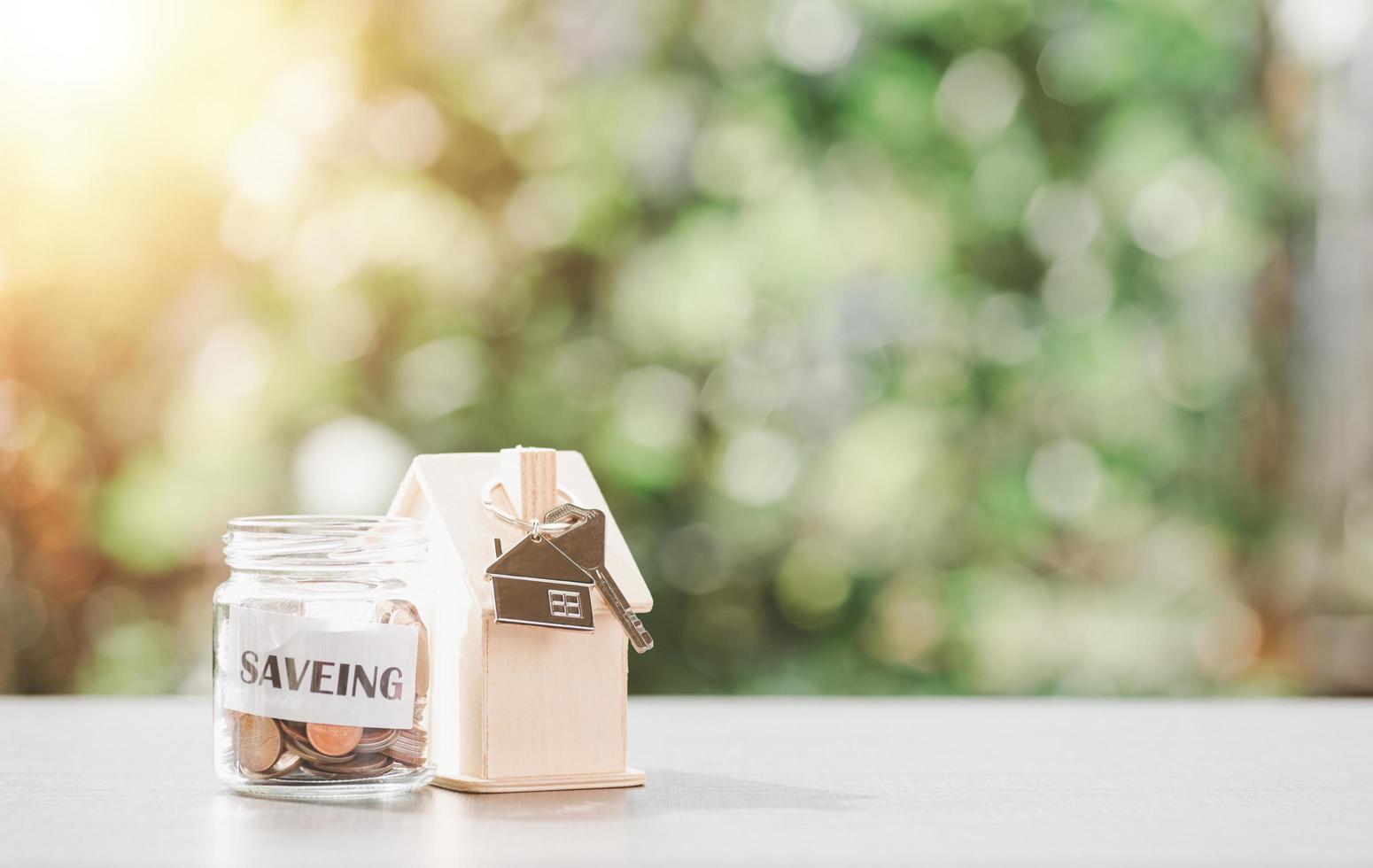 keychain, wooden house and glass jar, all on the table, money saving ideas for future home purchases, real estate, financial growth, building spending habits, housing investment photo