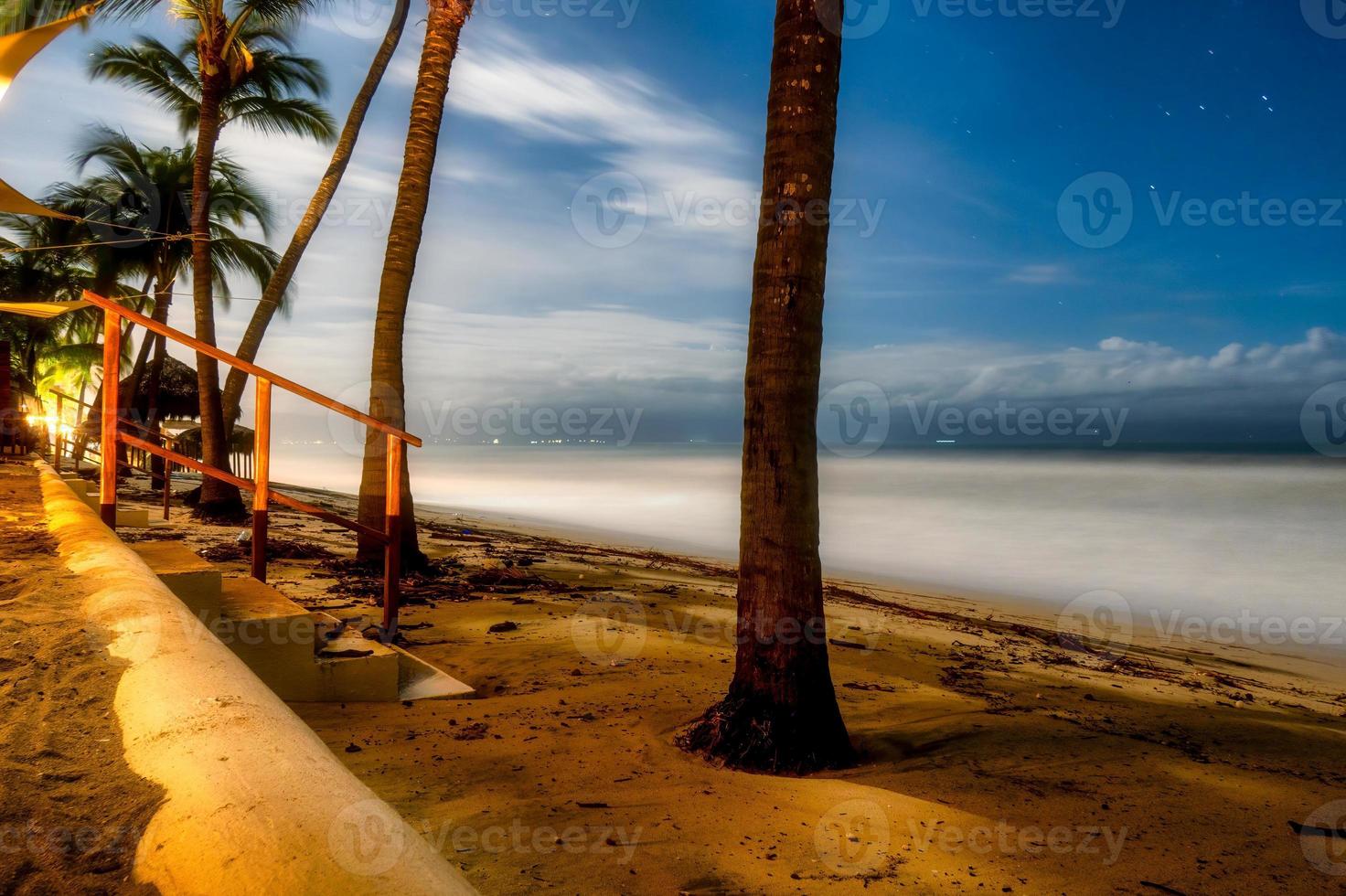 vista nocturna del mar con escaleras y palmeras foto