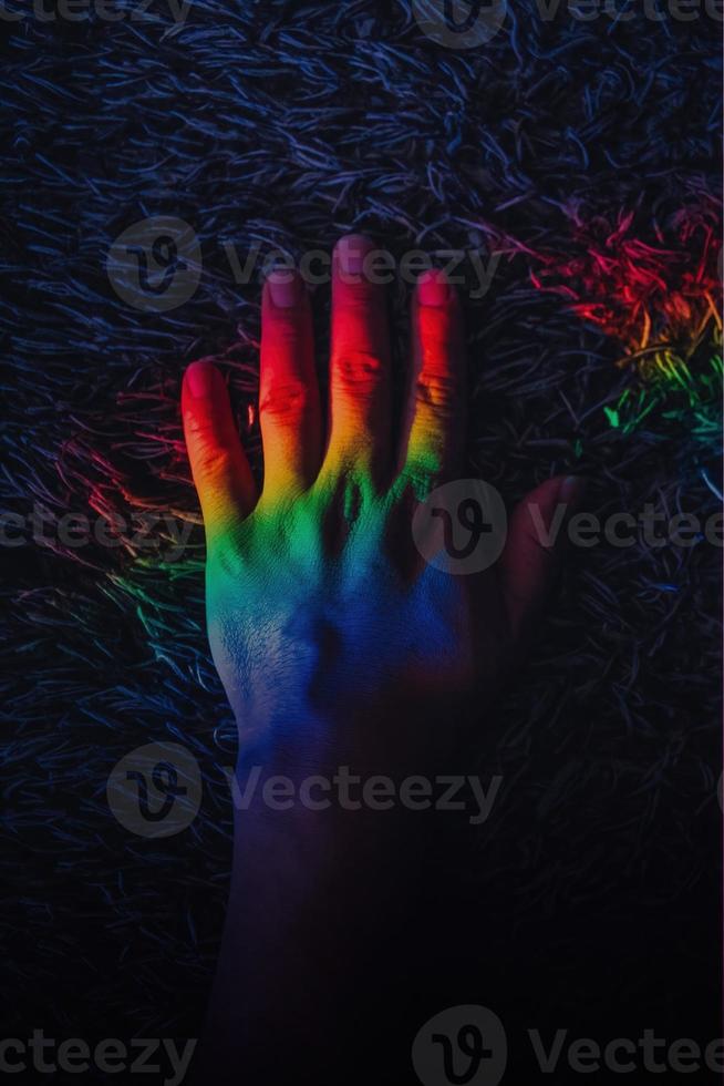 LGBT pride. Gay rights. Peace freedom. Diversity harmony. Graceful woman hands in blur rainbow lights. Iridescent blue red green yellow color gradient glow on dark empty space background. photo