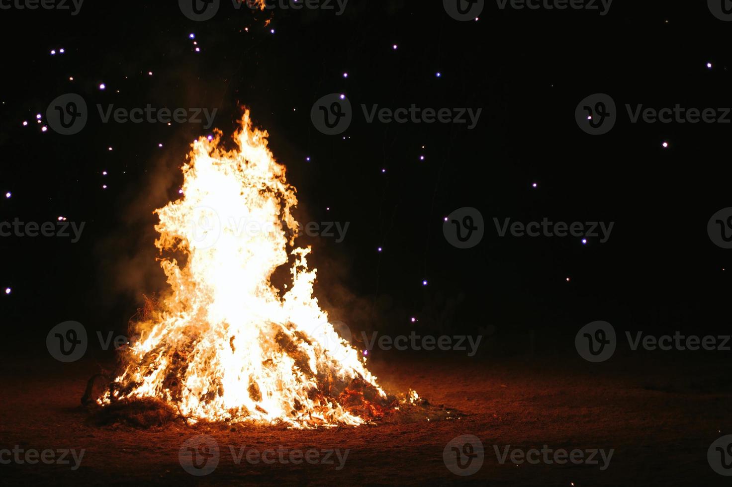 Fire embers particles over black background. Fire sparks background. Abstract dark glitter fire particles lights. bonfire in motion blur. photo