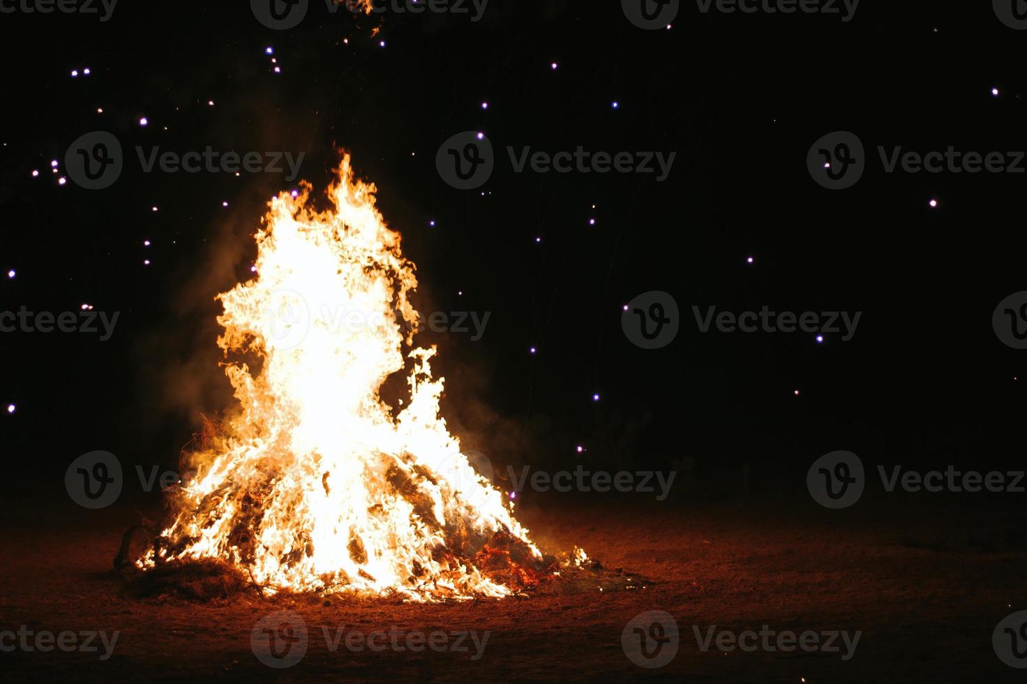 Partículas de brasas de fuego sobre fondo negro. fondo de chispas de fuego. luces de partículas de fuego de brillo oscuro abstracto. hoguera en el desenfoque de movimiento. foto