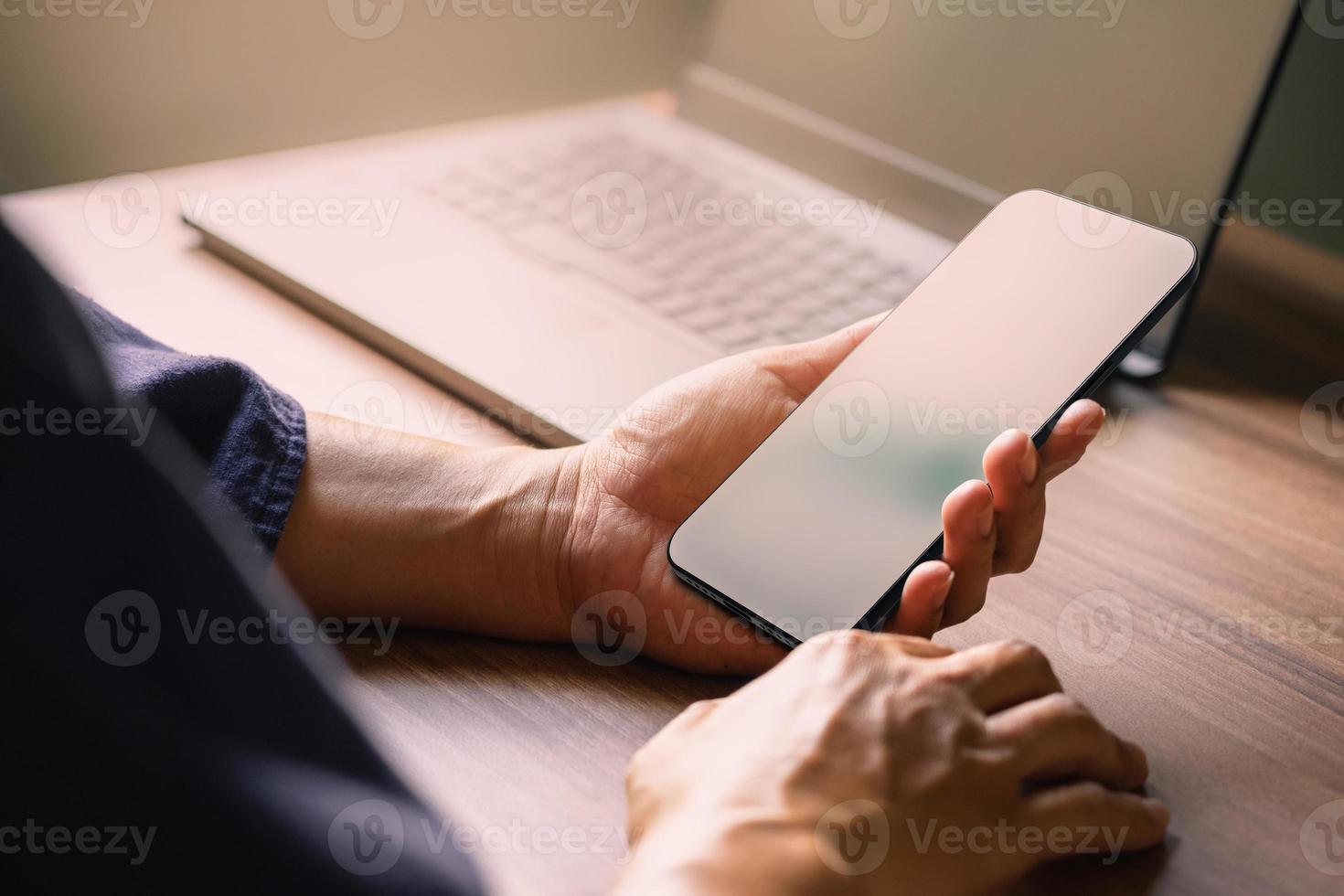 Mockup image of a man holding and using smartphone with blank desktop screen while working and drinking coffee in cafe. photo