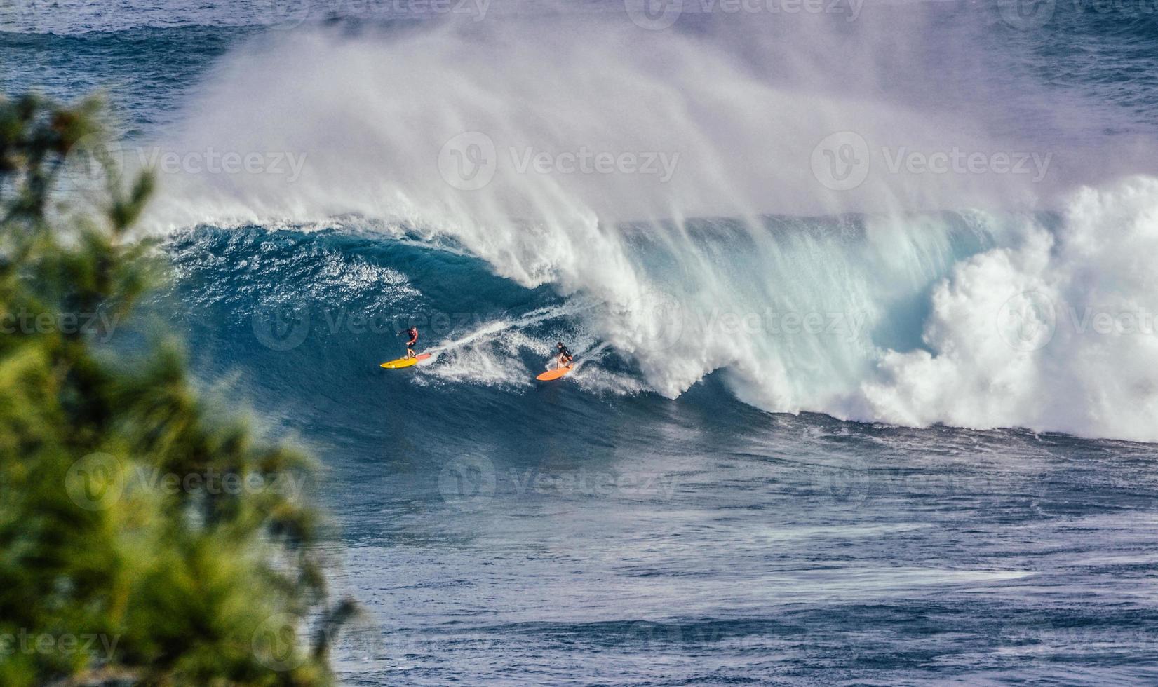 dos surfistas en el agua mientras las olas rompen en las mandíbulas foto