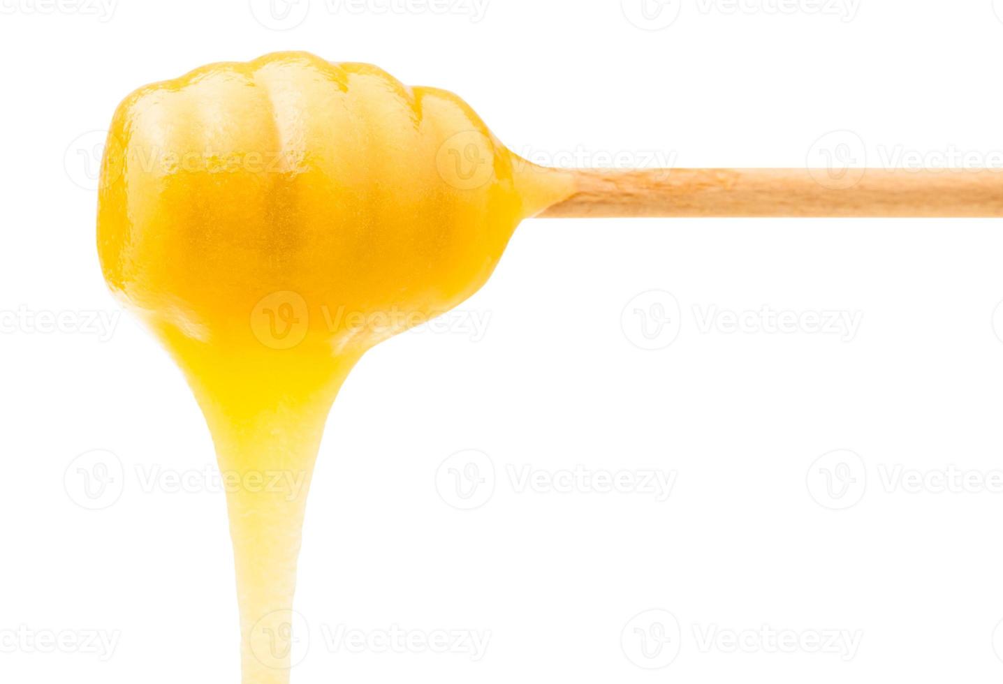 miel amarilla fluye desde un palo de madera aislado foto