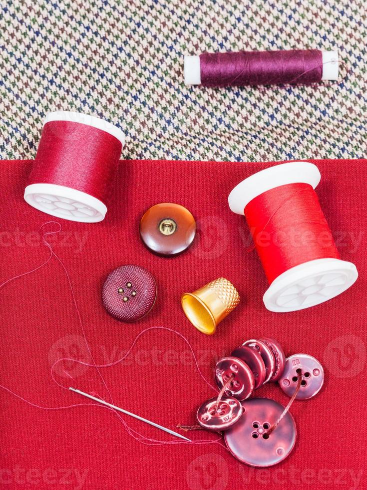 sewing thread, buttons, thimble on red cloth photo