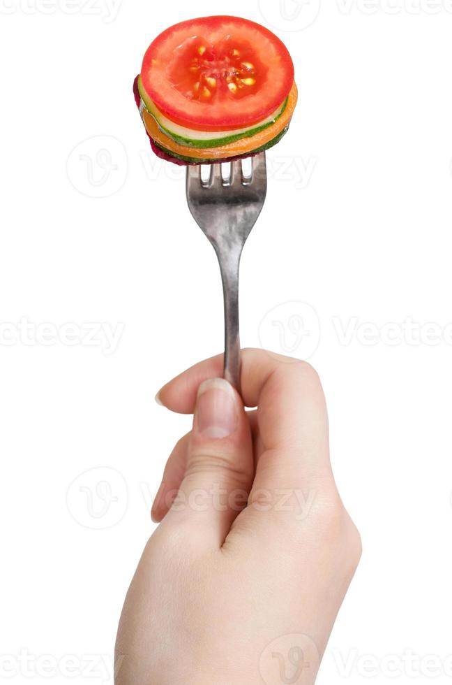 fork with impaled fresh sliced vegetables in hand photo