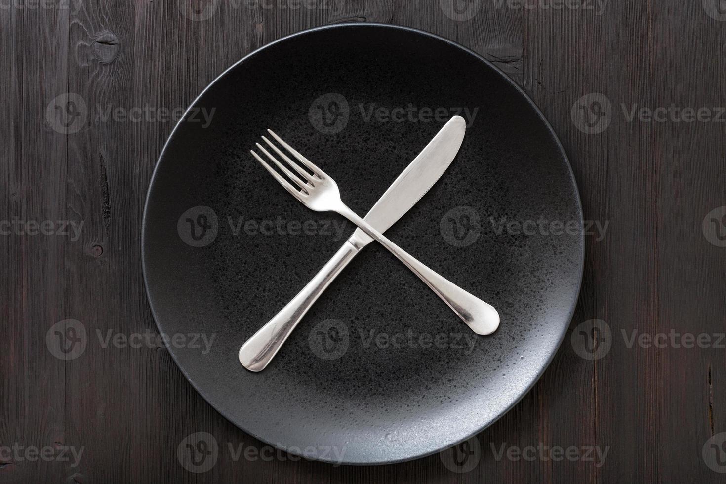 top view black plate with flatware on dark brown photo