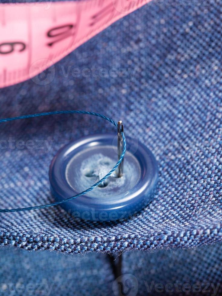 attaching of button to blue silk suit by needle photo