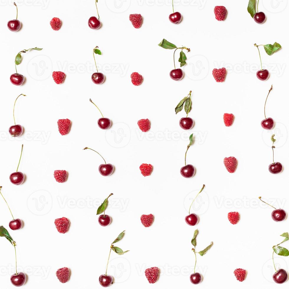 many raspberries and cherries arranged on square photo