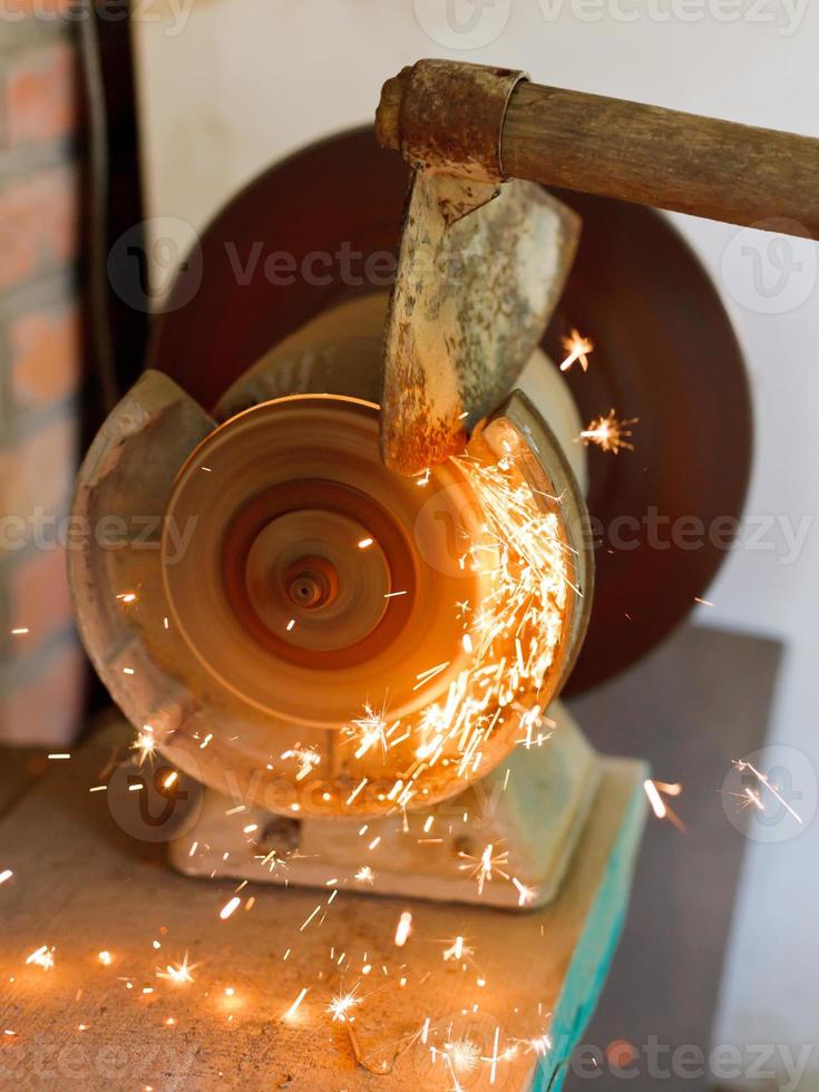 sharpening garden hoer using a grinding machine photo