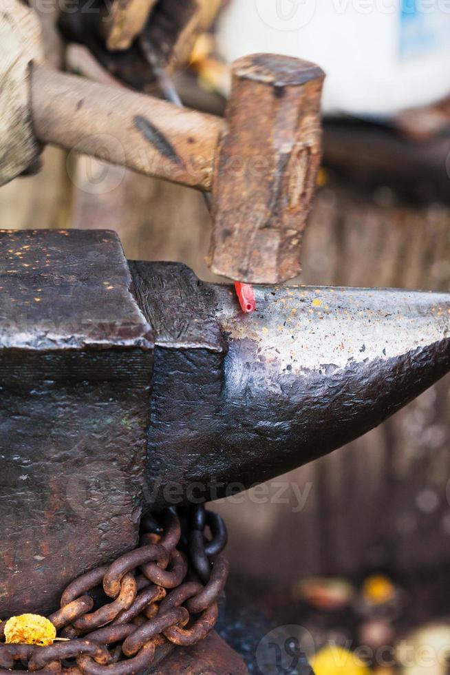 Blacksmith forges rod with sledgehammer on anvil photo