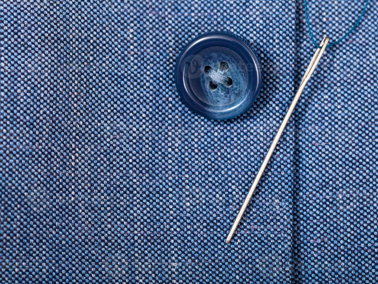 attaching of button to blue silk tissue by needle photo