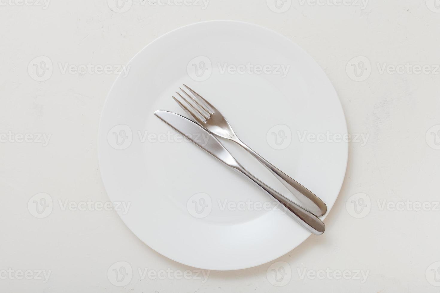 top view of white plate with flatware on white photo