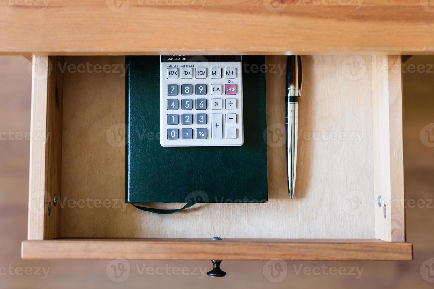 pen, calculator and notebook in open drawer photo