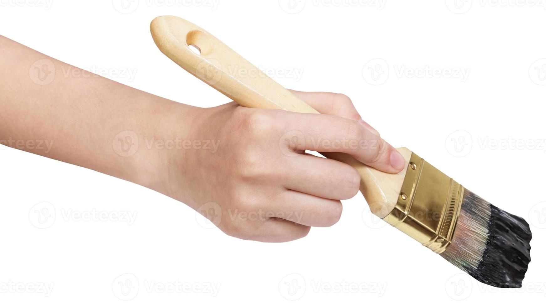 hand with flat paintbrush paints in black photo